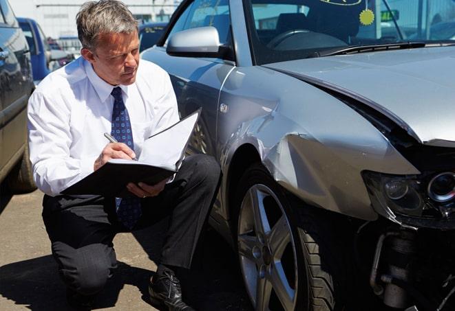 insurance adjuster inspecting a vehicle after a collision